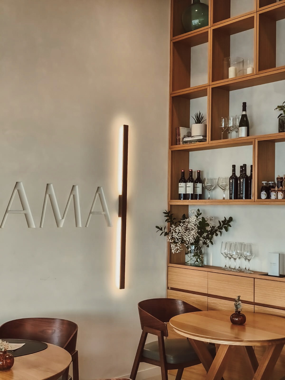 Rincón de la sala con el rótulo Nakama y la estantería de vinos