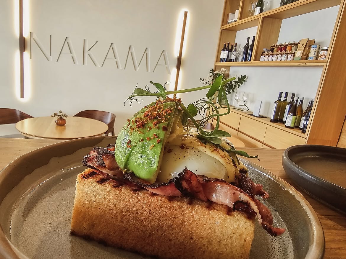 Tosta de bacon, huevo y aguacate junto al rótulo Nakama en relieve