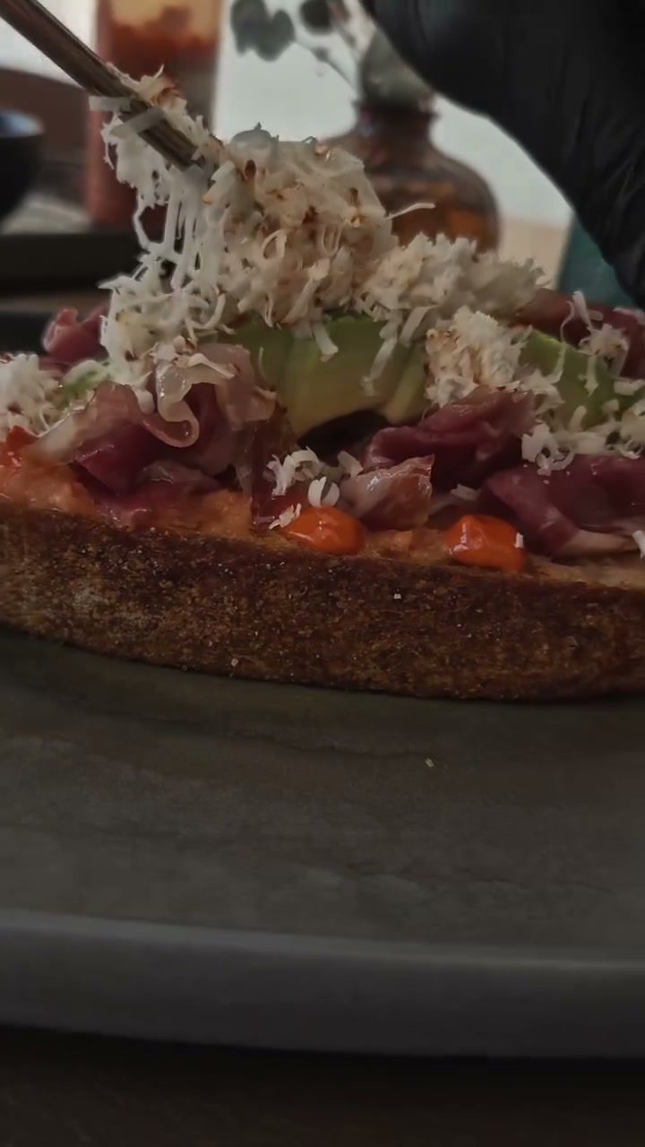 Brotes verdes colocándose con pinzas sobre una tosta terminada
