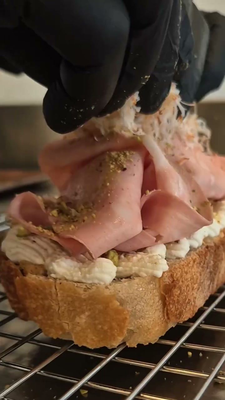 Loncha de jamón colocándose a mano sobre la tostada