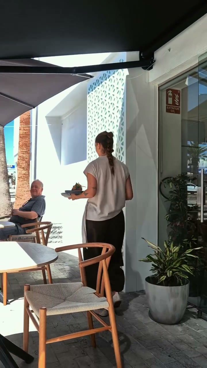 Terraza exterior de Nakama con pared calada y sillas de madera